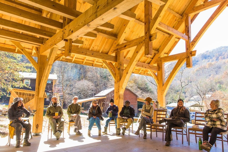 Students sitting in an open air timber frame teaching pavilion, holding a closing circle for a Tiny House Building workshop at Wild Abundance