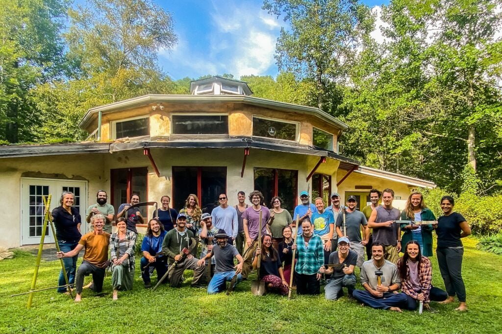 A class poses in front of the Council Hall for a group picture at the end of their permaculture design certificate course , hosted at Earthaven