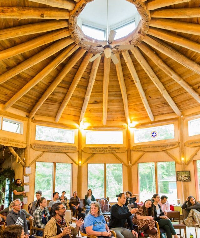 A permaculture design certification class holds their final presentations in the circular hand-built council hall at Earthaven Ecovillage