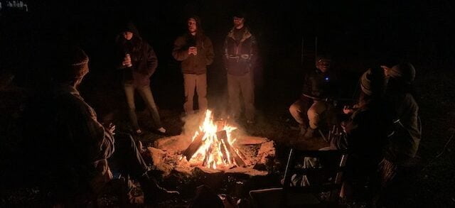 Students socializing at night around a campfire at the Paint Fork campus 