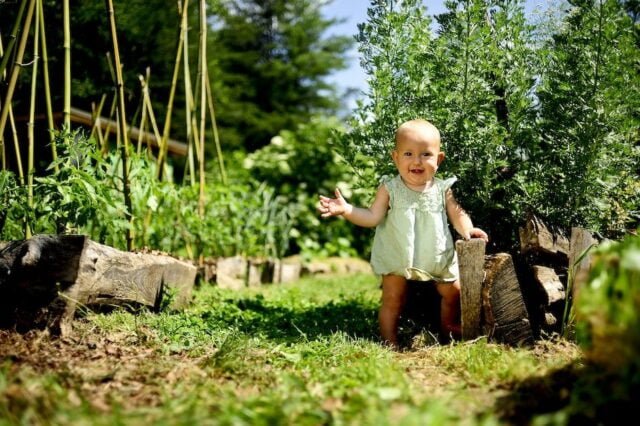 Natalie's daughter Hazel as a baby taking first steps in the garden at Wild Abundance's original campus