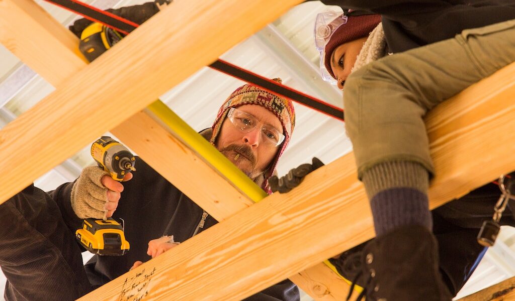 A team of students works on attaching rafters for the roof during a Tiny House building workshop at Wild Abundance.