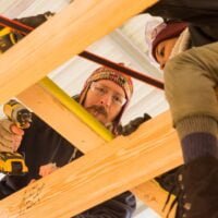 A team of students works on attaching rafters for the roof during a Tiny House building workshop at Wild Abundance.