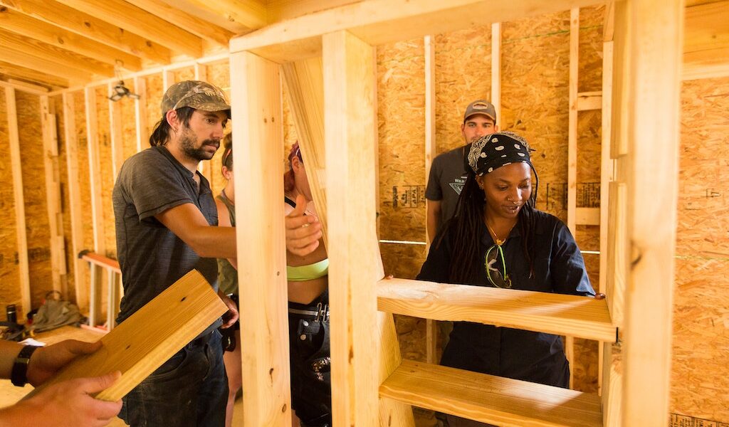 A teacher guides a student on how to attach custom stairs for a loft during a Tiny House building workshop at Wild Abundance.