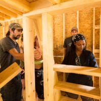 A teacher guides a student on how to attach custom stairs for a loft during a Tiny House building workshop at Wild Abundance.
