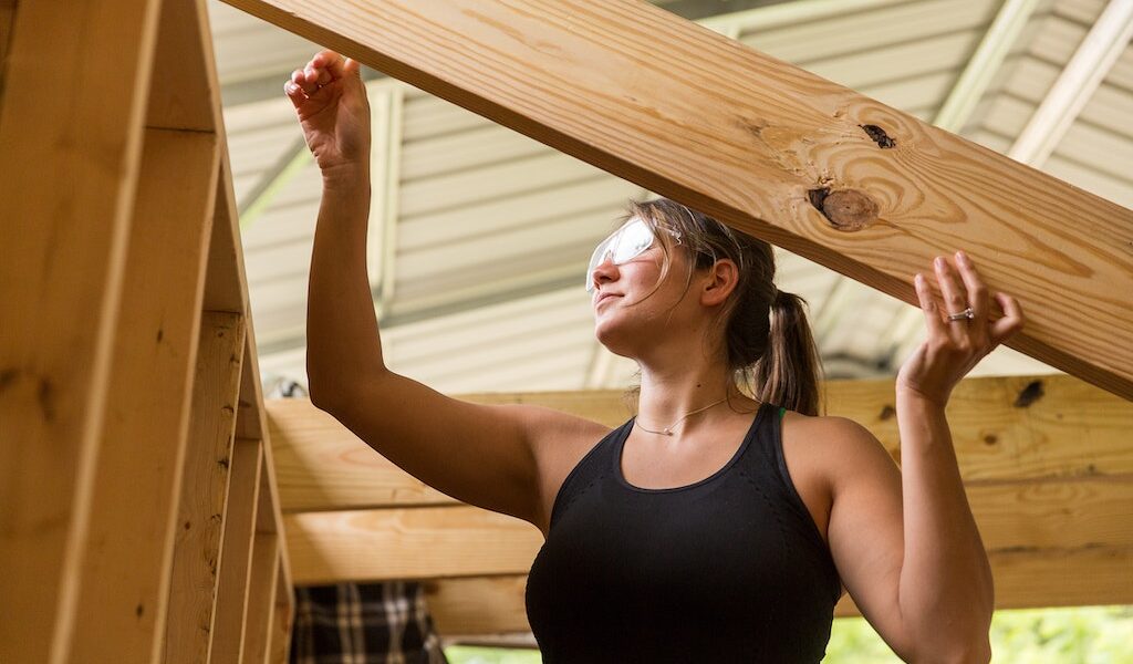 A student lifts a rafter into place during a Tiny House building workshop at Wild Abundance.