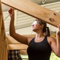 A student lifts a rafter into place during a Tiny House building workshop at Wild Abundance.