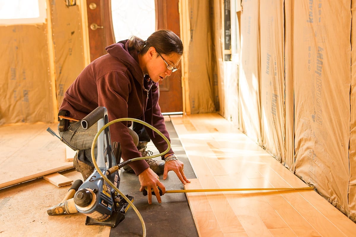 Students installing hardwood flooring during training.