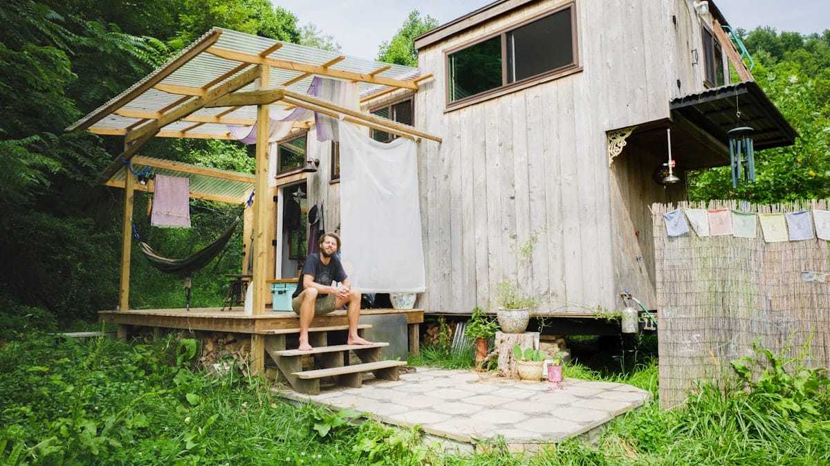 Jazz In Reverse-47 (1)-exterior mason tiny home outdoor shower porch hammock A tiny house owner-builder plays music on his porch, utilizing the outdoor space he's constructed around his tiny home to maximize living space