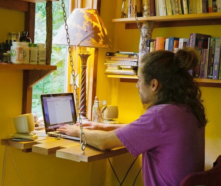 P1022876-fold out desk for laptop in tiny home A person works on their laptop taking a free online course