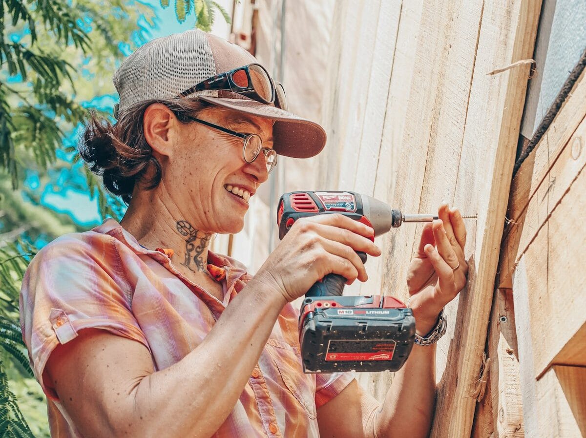 Photo Jul 28, 7 10 46 PM-impact driver Woman using an impact driver to attach siding to a tiny house in a workshop at Wild Abundance