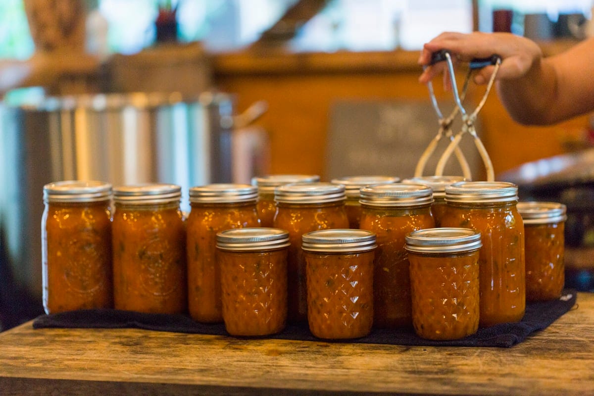 STew-7278-canning sauce_-canning sauce A batch of freshly canned tomato sauce made with garden ripened tomatoes and herbs sits on the the kitchen island in the Wild Abundance outdoor kitchen
