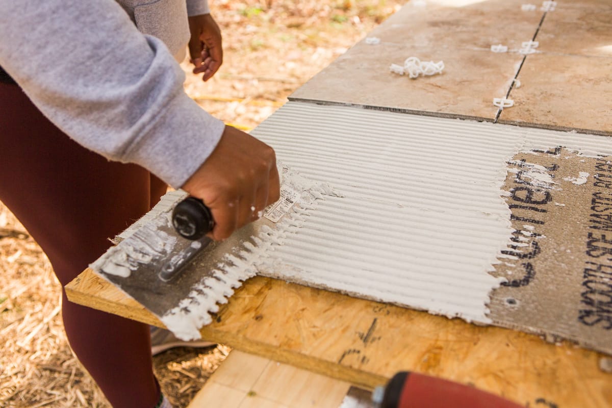 1-Handy Homeowner Bootcamp 2025 A student learns to lay tile in the Handy Homeowner Bootcamp at Wild Abundance