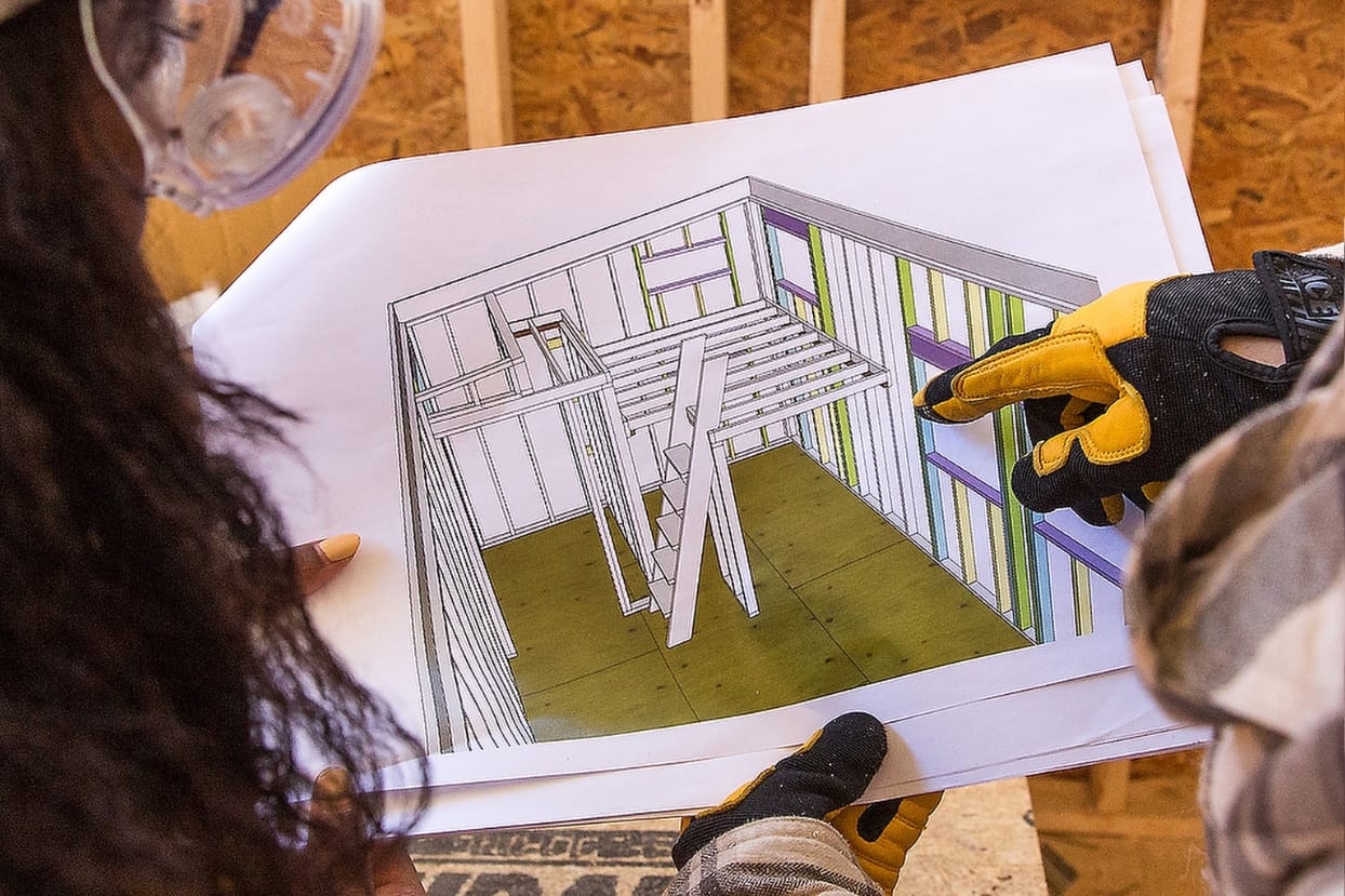 tiny house plans in hands DIY tiny home builders look at the plans they modified from Wild Abundance's "Helene House" base model plans for sale at a great deal for just 27$