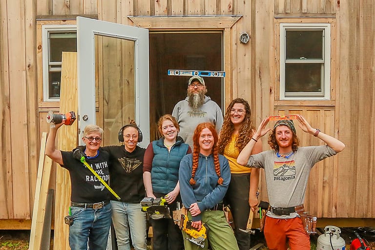 Carpentry training program Students smile for a group picture in front of the TIny House they built and finished at Wild Abundance