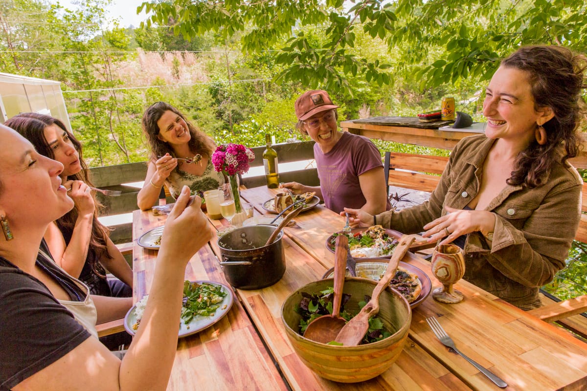 Gaia leading staff meeting with food at Wild Abundance 2025-1200-Current- Gaia Goldhill, the executive director, is seen smiling as she leads a staff meeting with food at Wild Abundance