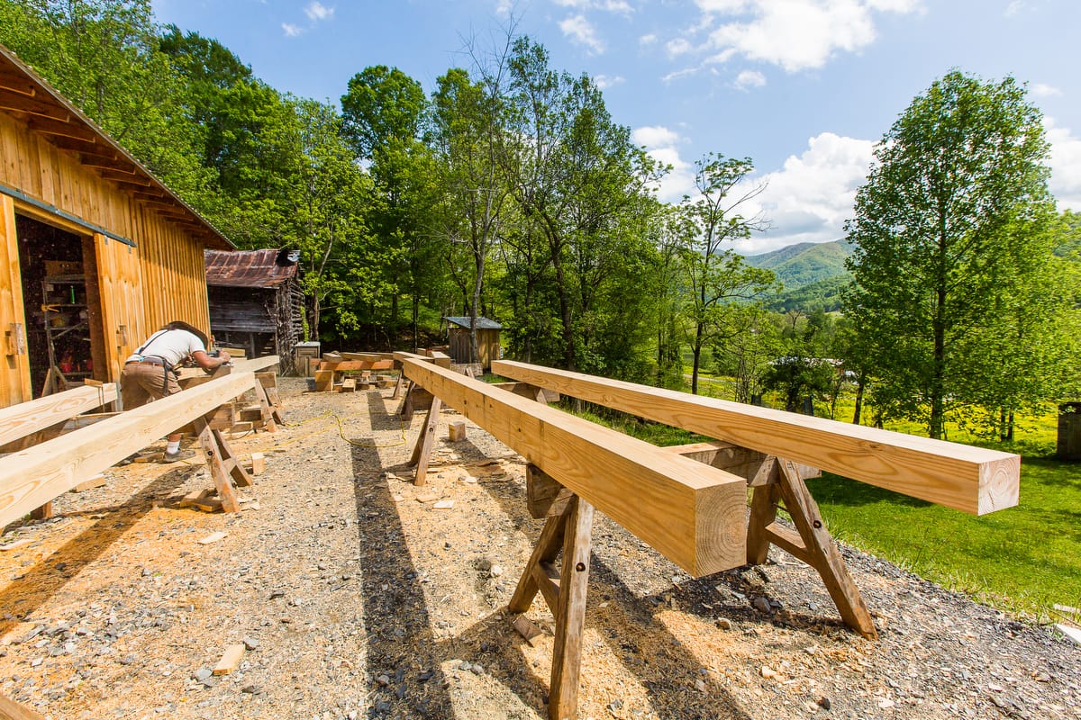 The exterior of Ivy Creek Timber Framing Workshop with a pile of stacked beams