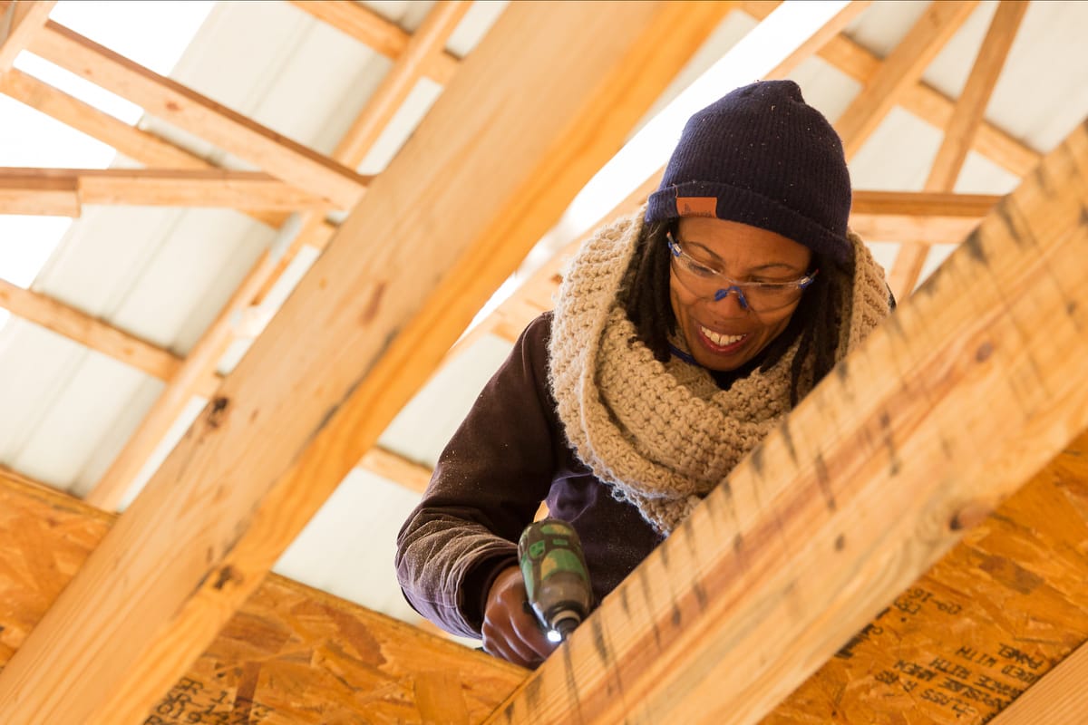A woman works on a crew building a Tiny House during a building class at Wild Abundance