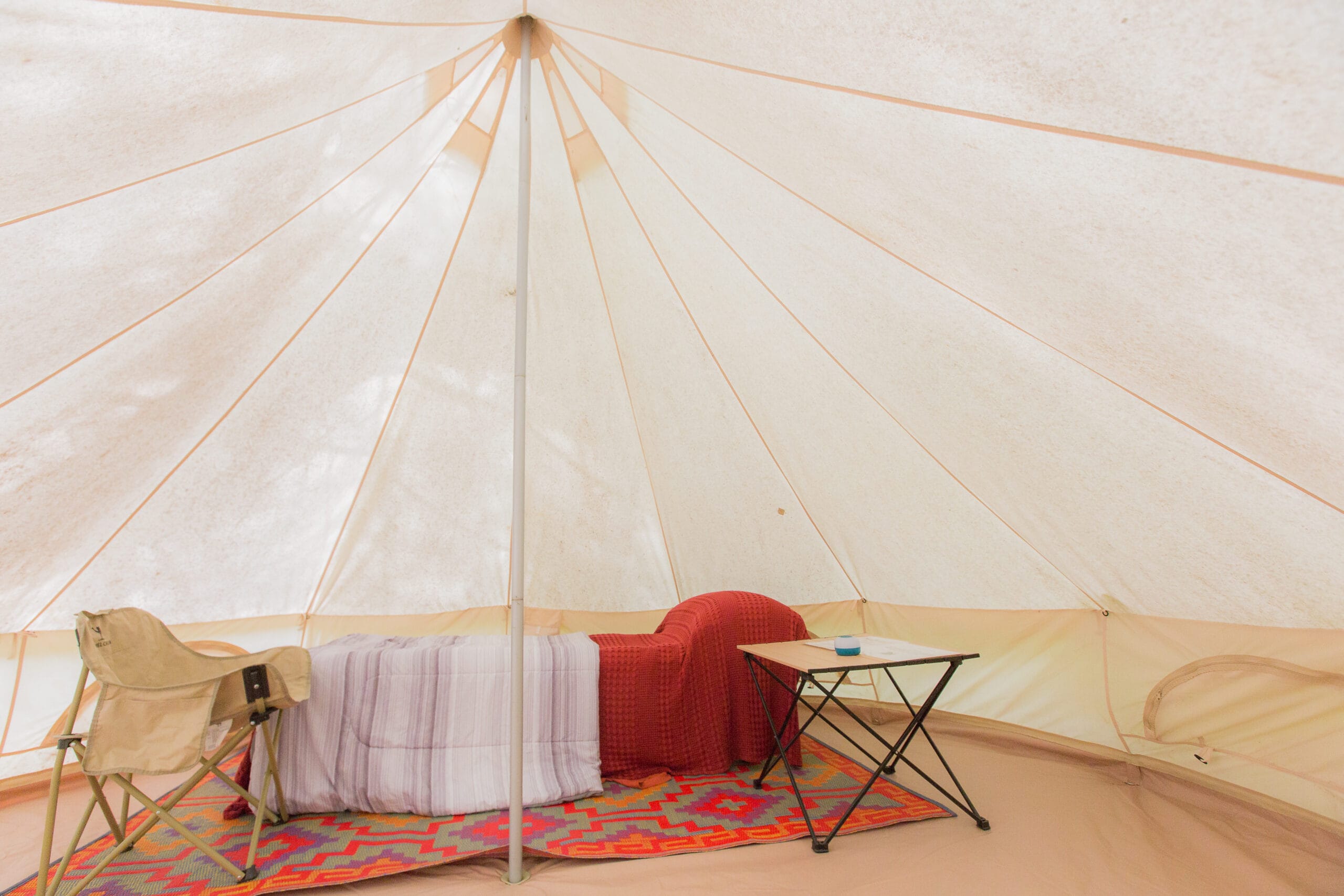 Inside each bell tent is a cot with bedding and a chair.