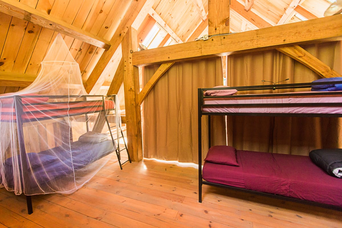 There are mosquito screens available and curtains for privacy in this shared dorm loft with 3 bunkbeds for students to book during their workshops at Wild Abundance.